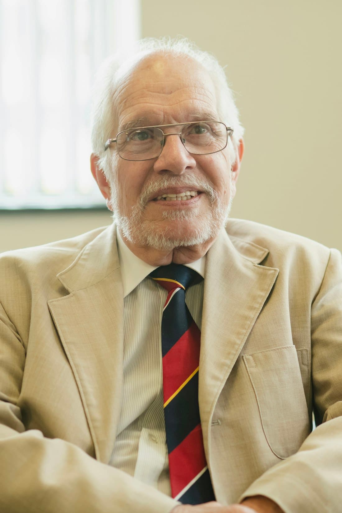 An established business owner in his seventies, seated in his office
